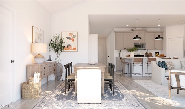 dining space with light hardwood / wood-style flooring and vaulted ceiling