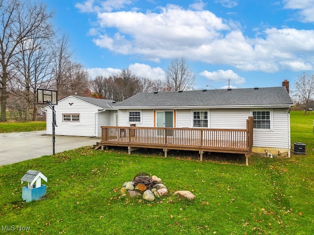 back of property with a lawn, central AC unit, a fire pit, and a deck