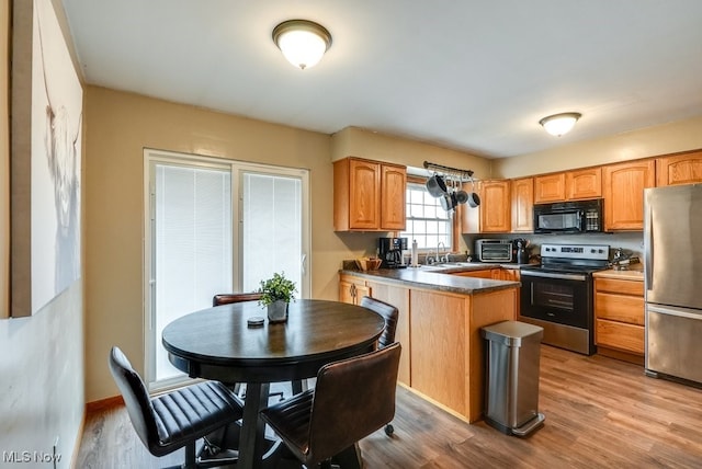 kitchen with sink, stainless steel appliances, and light hardwood / wood-style floors