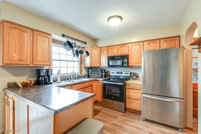 kitchen featuring sink, light brown cabinets, light hardwood / wood-style flooring, kitchen peninsula, and appliances with stainless steel finishes