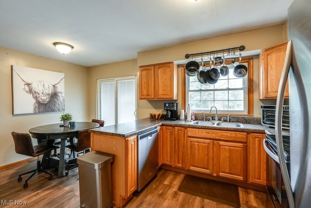 kitchen with kitchen peninsula, sink, hardwood / wood-style floors, and appliances with stainless steel finishes