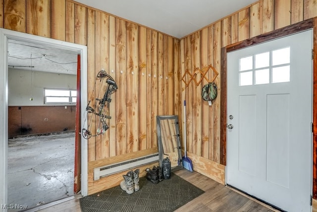 foyer entrance featuring wood walls, a baseboard heating unit, and hardwood / wood-style flooring