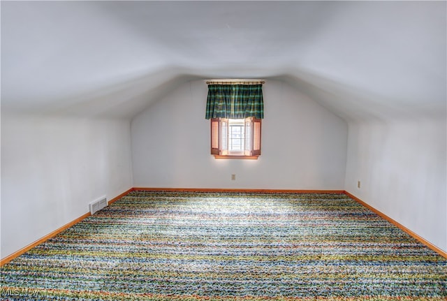 additional living space featuring carpet flooring and vaulted ceiling