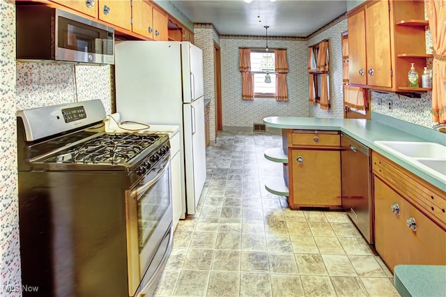 kitchen with sink, kitchen peninsula, stainless steel appliances, and hanging light fixtures