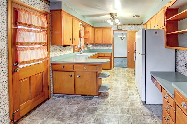 kitchen featuring ceiling fan with notable chandelier, white fridge, decorative backsplash, and sink