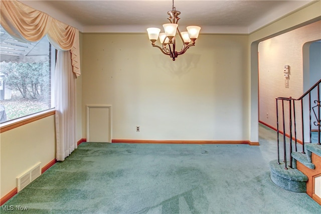 carpeted spare room featuring an inviting chandelier