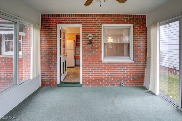 unfurnished sunroom with ceiling fan