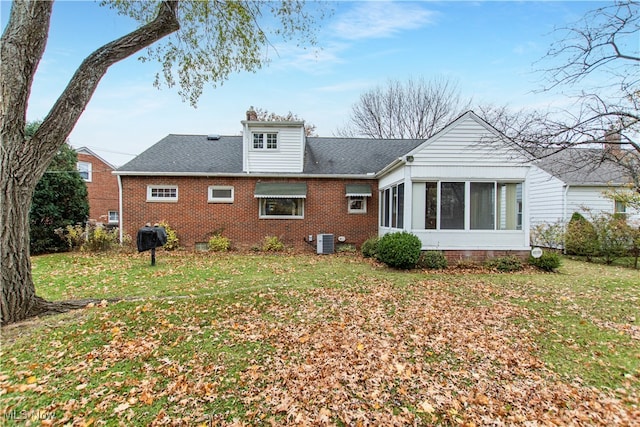 rear view of property featuring central air condition unit, a sunroom, and a yard