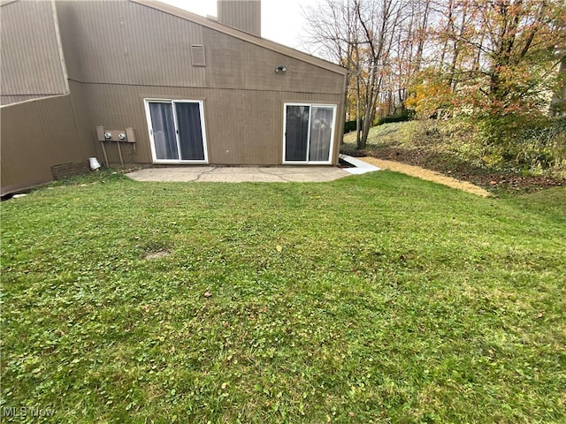 rear view of house featuring a lawn and a patio