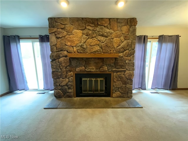 unfurnished living room featuring a stone fireplace and carpet floors