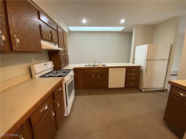 kitchen with kitchen peninsula, a skylight, white appliances, light colored carpet, and sink