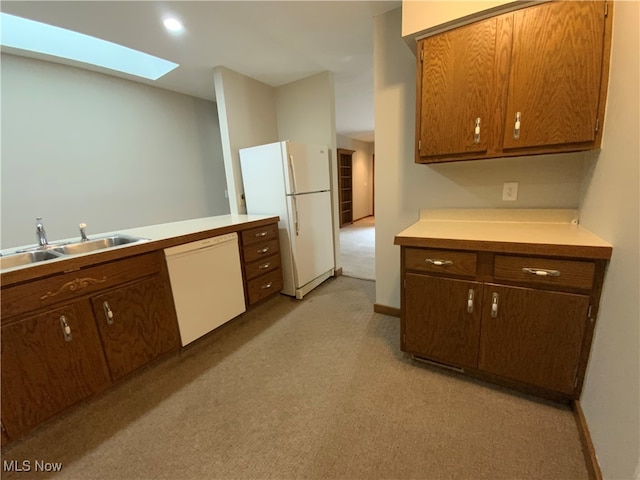 kitchen featuring white appliances, sink, light carpet, and a skylight