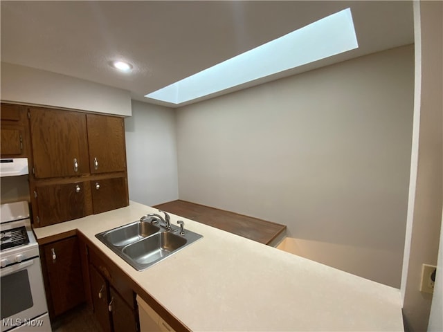 kitchen featuring white appliances, a skylight, range hood, and sink