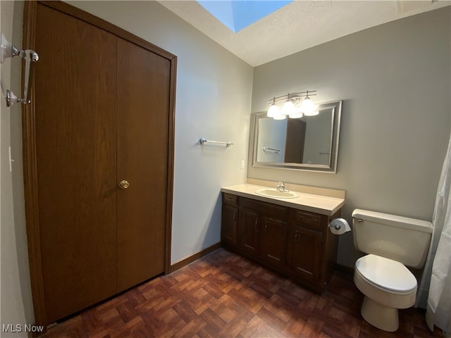 bathroom with a skylight, parquet floors, a textured ceiling, toilet, and vanity