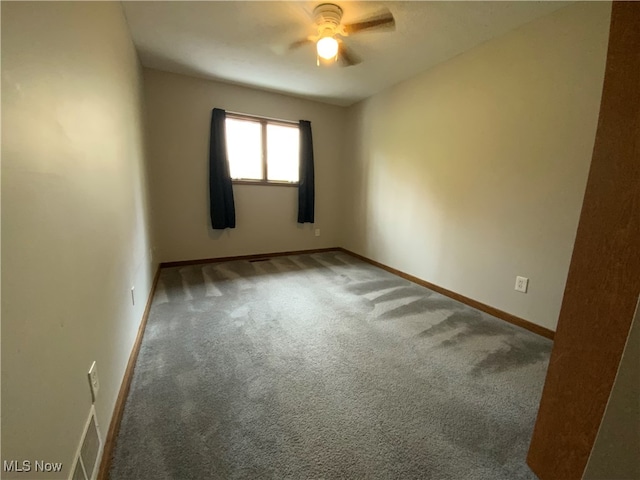 unfurnished room with ceiling fan and dark carpet