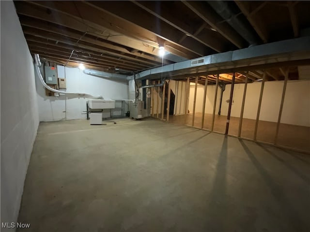 basement with electric panel, heating unit, and sink