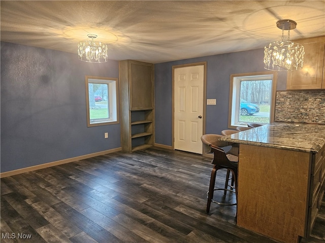 unfurnished dining area featuring a notable chandelier, dark wood-type flooring, and a wealth of natural light