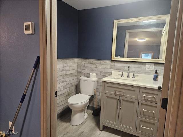 bathroom featuring hardwood / wood-style floors, vanity, toilet, and tile walls