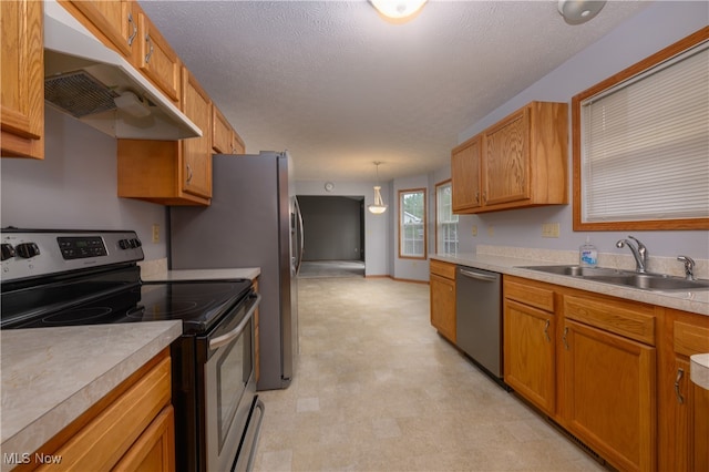 kitchen with a textured ceiling, sink, decorative light fixtures, and appliances with stainless steel finishes