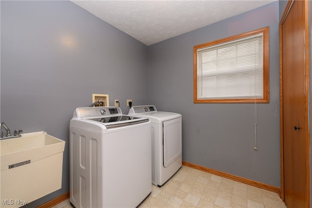 clothes washing area featuring a textured ceiling, washing machine and dryer, and sink