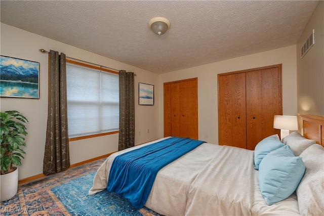 bedroom with a textured ceiling and multiple closets