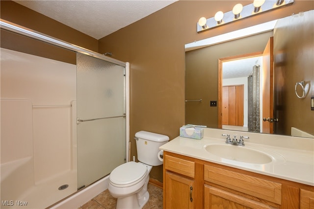 bathroom featuring vanity, tile patterned flooring, toilet, a textured ceiling, and walk in shower