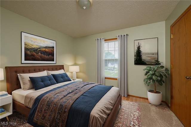 bedroom featuring light hardwood / wood-style flooring and a textured ceiling