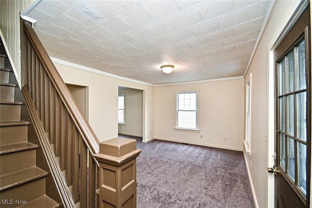 foyer entrance featuring dark colored carpet and crown molding