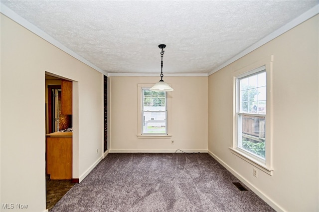 empty room with a textured ceiling, dark carpet, and a wealth of natural light