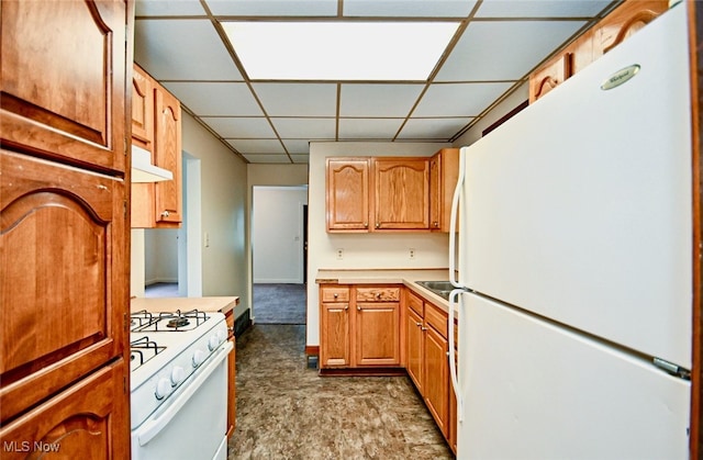 kitchen featuring a drop ceiling and white appliances