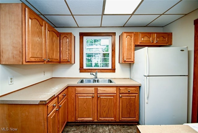 kitchen with sink, a drop ceiling, and white refrigerator