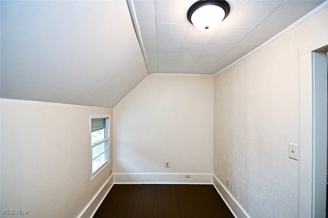 additional living space featuring dark wood-type flooring and vaulted ceiling