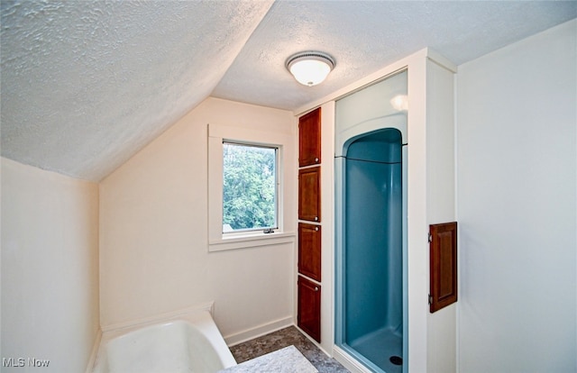 bathroom featuring separate shower and tub, lofted ceiling, and a textured ceiling