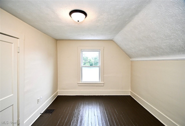 additional living space with lofted ceiling, a textured ceiling, and dark wood-type flooring