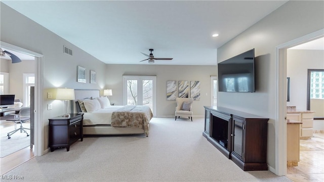 bedroom featuring ceiling fan, light colored carpet, and connected bathroom