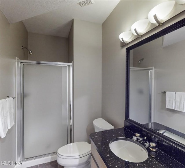 bathroom with a textured ceiling, vanity, toilet, and walk in shower