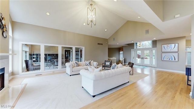 living room with french doors, high vaulted ceiling, light wood-type flooring, and an inviting chandelier