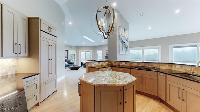 kitchen featuring pendant lighting, a center island, sink, and dark stone counters