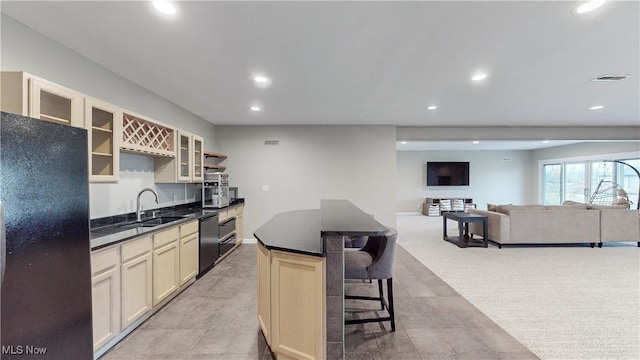 kitchen featuring a center island, cream cabinets, black appliances, sink, and a breakfast bar area