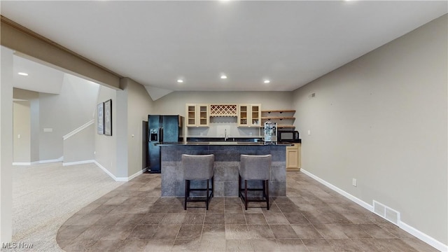 kitchen with light colored carpet, sink, black appliances, a center island, and a breakfast bar area