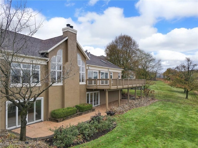 rear view of house with a wooden deck and a yard