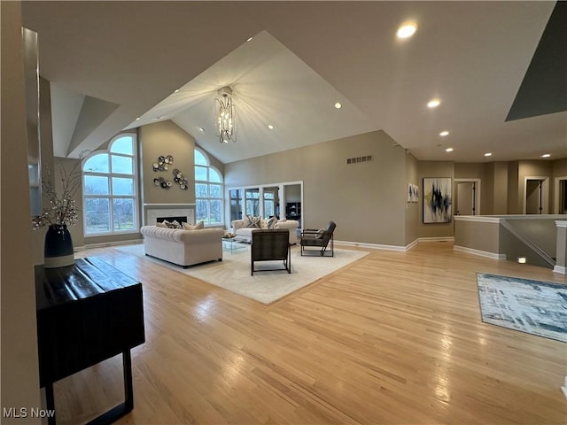 living room featuring a chandelier, light hardwood / wood-style floors, and high vaulted ceiling