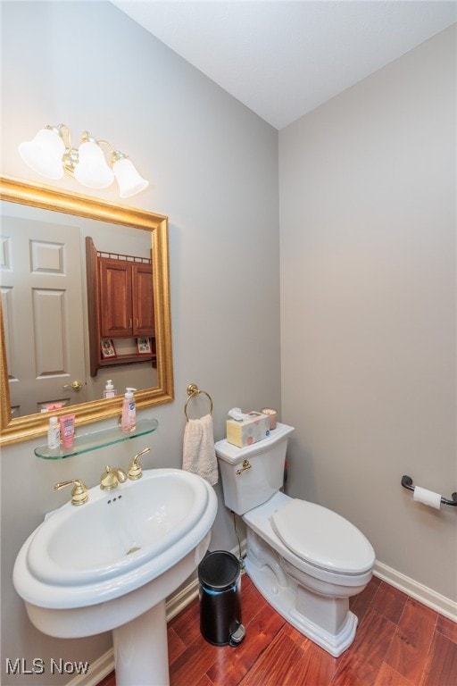 bathroom with hardwood / wood-style flooring, toilet, and sink