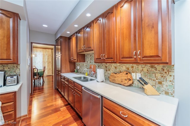 kitchen with backsplash, light hardwood / wood-style floors, stainless steel dishwasher, and sink