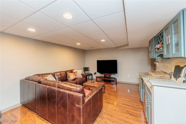 living room with a paneled ceiling and light hardwood / wood-style floors