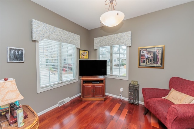 sitting room with dark wood-type flooring and a healthy amount of sunlight