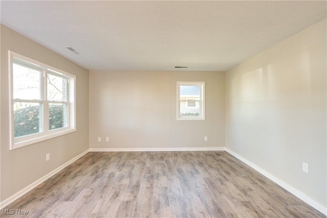 spare room featuring a healthy amount of sunlight and light hardwood / wood-style flooring