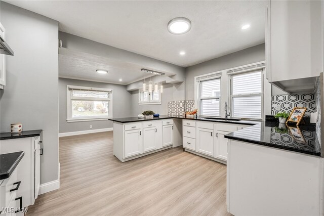 kitchen with kitchen peninsula, plenty of natural light, white cabinets, and light hardwood / wood-style floors