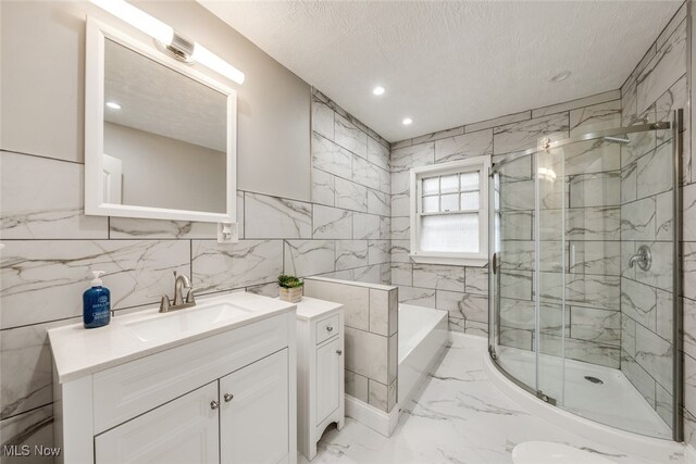 bathroom with vanity, a textured ceiling, and shower with separate bathtub