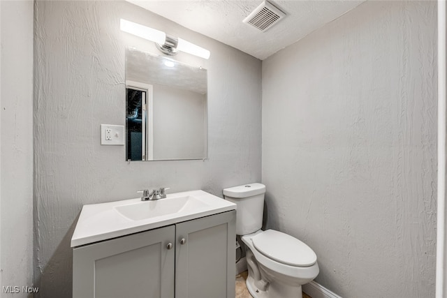 bathroom featuring vanity, a textured ceiling, and toilet